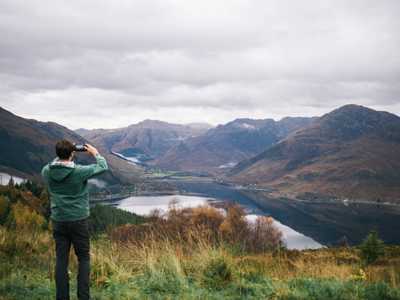 Man taking photo of the Five Sisters of Kintail mountain range