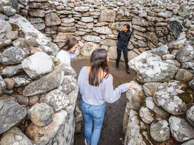 Two young women standing inside the circular Clava Cairn burial site