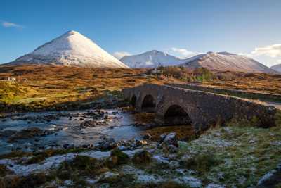Sligachan Bridge over river surrounded by scenic Highlands and snowy hills on the Isle of Skye