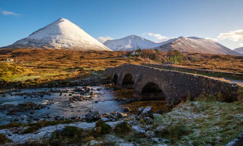 Sligachan Bridge over river surrounded by scenic Highlands and snowy hills on the Isle of Skye