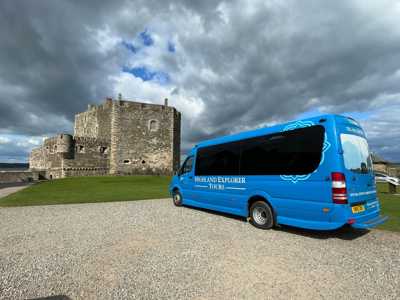 Blue Highland Explorer mini bus parked in front of Blackness Castle