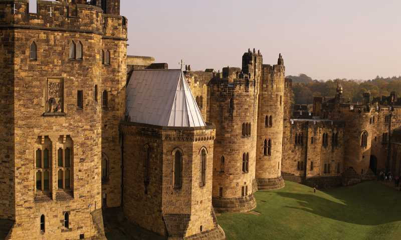 Exterior of Alnwick Castle with majestic stone walls resembling school of Hogwarts from Harry Potter