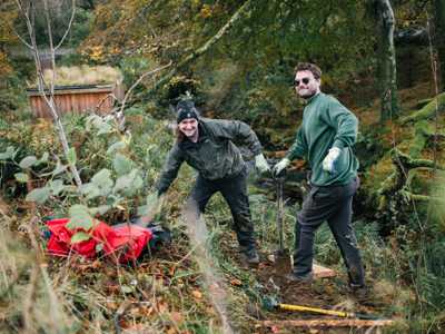 two young men widening path in tomore forest's lush area