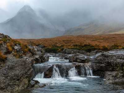 Fairy Pools waterfalls on a misty day in winter with mysterious mountain backdrop