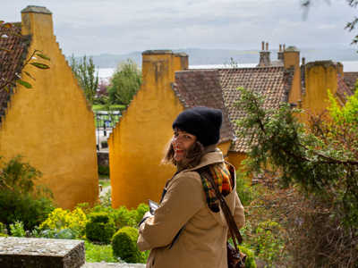 Young woman enjoying the views of yellow houses in Culross village 