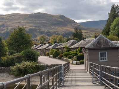 Idyllic harbour and pier of Luss with views of distant hills and traditional stone houses