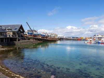 Mallaig harbour with fishing huts and clear blue water