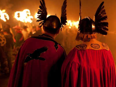 Two men dressed as Vikings with red cloaks and helmets during the Up Helly Aa torchlight procession