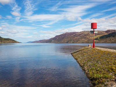 Shores of Loch Ness on a sunny day with blue skies and hills in the background