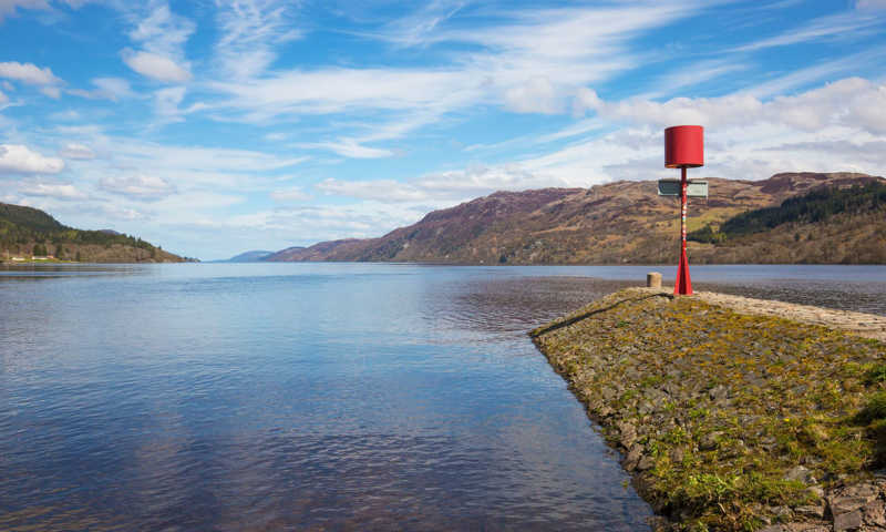 Shores of Loch Ness on a sunny day with blue skies and hills in the background