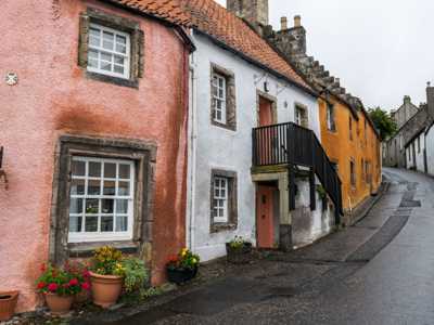 Windy alleyway in Culross village with colorful housefronts and flower baskets