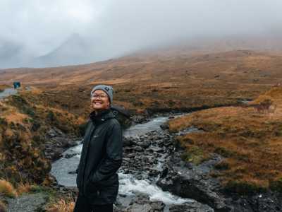 Young woman dressed warm and walking along the Fairy Pools on isle of Skye