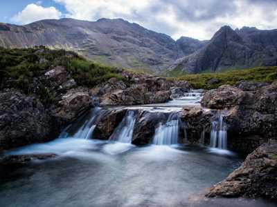Fairy Pools on the Isle of Skye, featuring crystal-clear waters cascading over rocks, surrounded by rugged hills