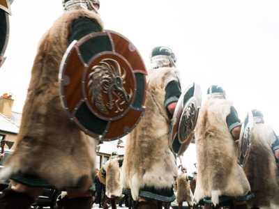 Viking parade with men in fur coats and helmets, carrying decorated shields