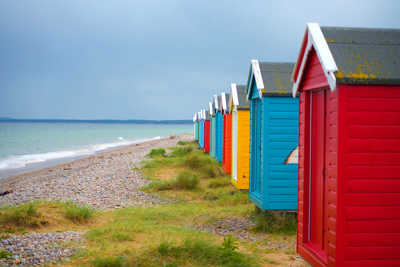Findhorn Beach with colorful beach huts lined along the shore, set against golden sands and a calm sea