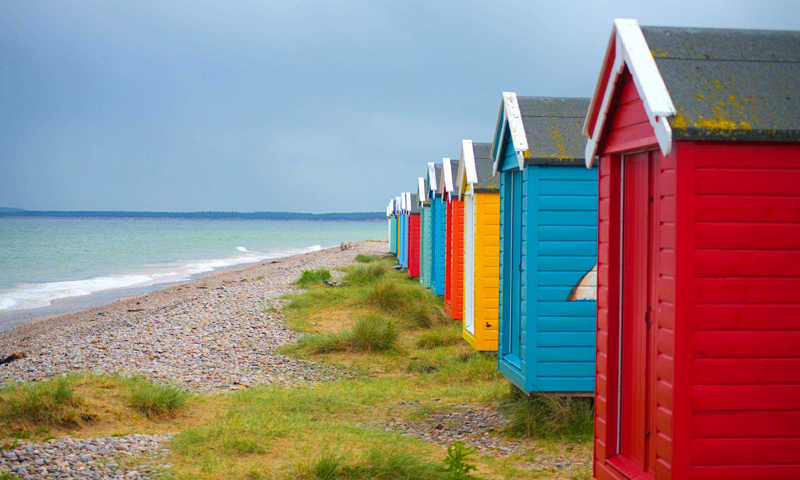 Findhorn Beach with colorful beach huts lined along the shore, set against golden sands and a calm sea