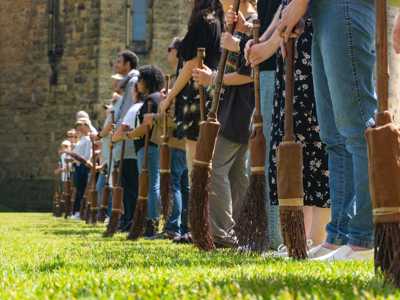 People standing in a line with their broomsticks at Alnwick Castle
