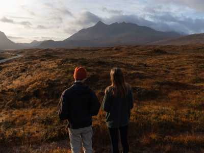 Yougn couple enjoyigngviews of the Cuillin Mountains on isle f Skye during a wintry sunset
