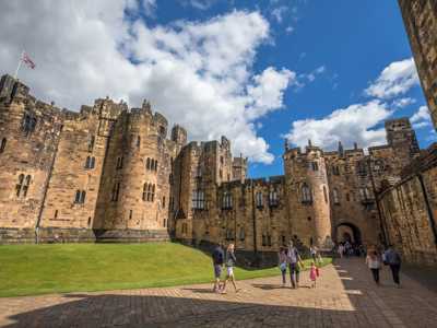 Inside Alnwick Castle's courtyard with large grass patch resembling training grounds of Hogwarts from Harry Potter