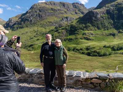 Elderly couple taking a photo together with Glen Coe in the Background