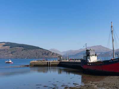 Inveraray Pier with colourful boat bobbing in peaceful lochshore