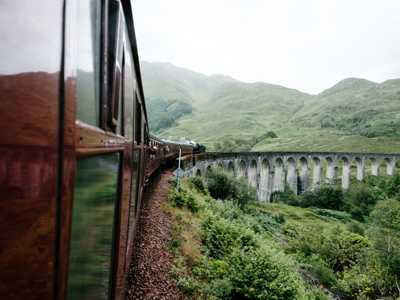 View of the Glenfinnan Viaduct stone arches from inside the red carriages of the Jacobite Steam Train