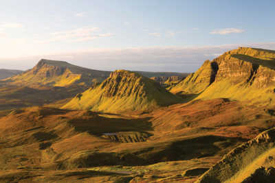 Isle of Skye at sunset, with dramatic mountain silhouettes set against vibrant skies and golden light
