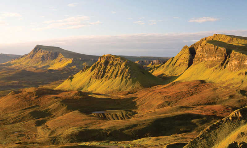 Isle of Skye at sunset, with dramatic mountain silhouettes set against vibrant skies and golden light